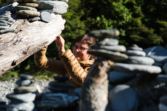 Frau baut ein weiteres Steinmännchen bei den Fantail Falls
