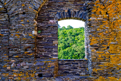 Ein buntes Fenster in einer Steinmauer der Ruine Schmidtburg