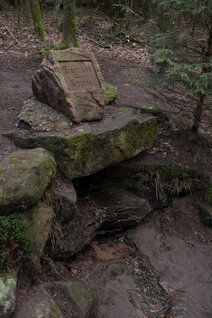 Eine von Sandsteinbrocken eingefasst Quelle mit der Inschrift 'Siegfriedsbrunnen'
