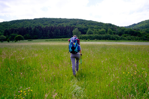 A female hiker walking through a grass field near Kirn