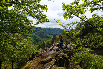 Frau sitzt auf einem Felsen am Mehrholzblick auf dem Wispertalsteig