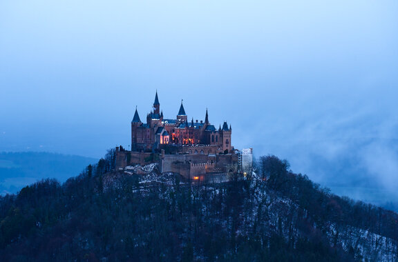Die beleuchtete Burg Hohenzollern auf dem Berg im Morgengrauen.